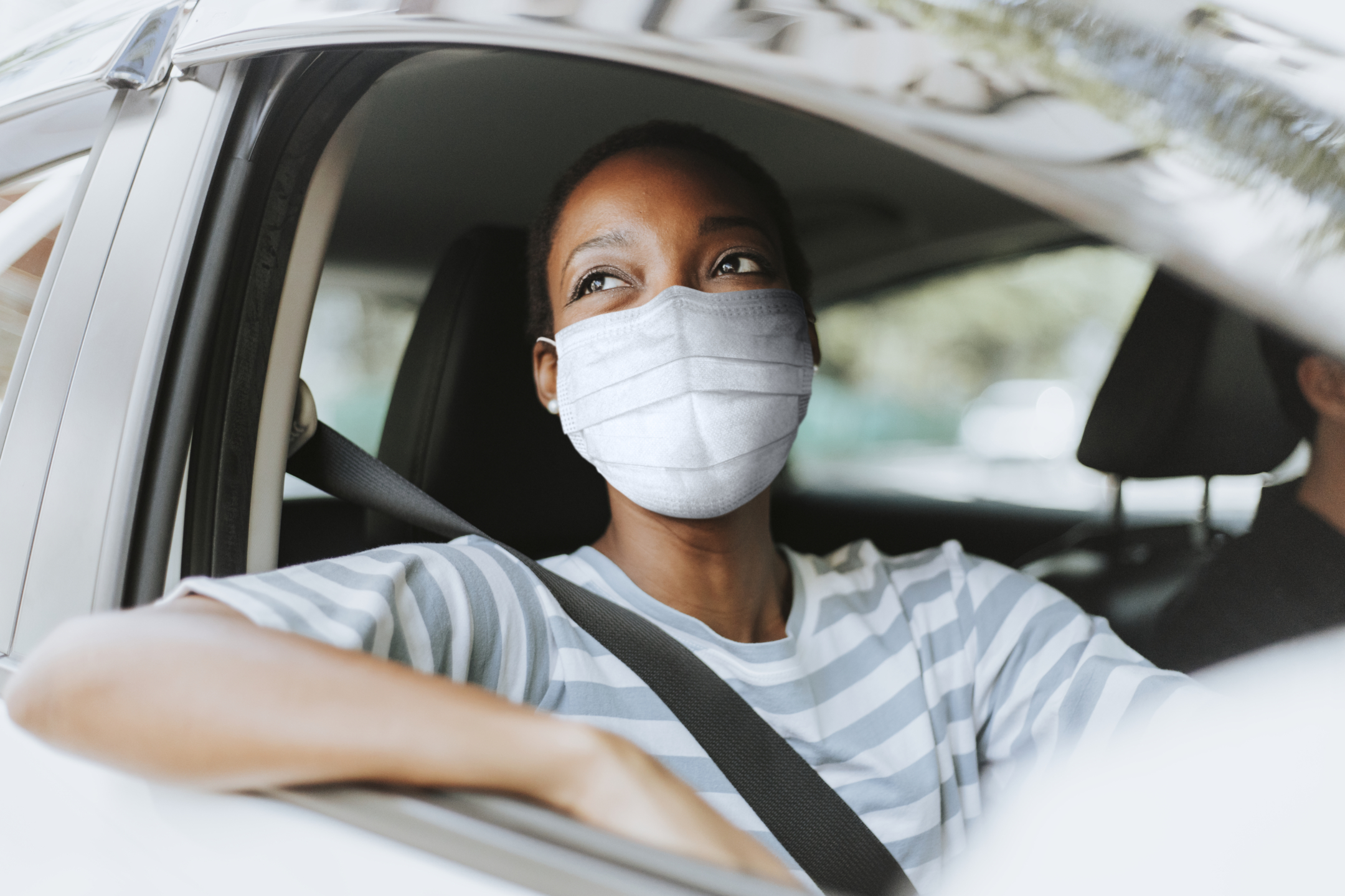 Woman with mask at drive thru with her car